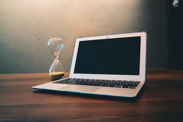 Laptop and hourglass on a desk symbolizing PhD application planning and deadlines