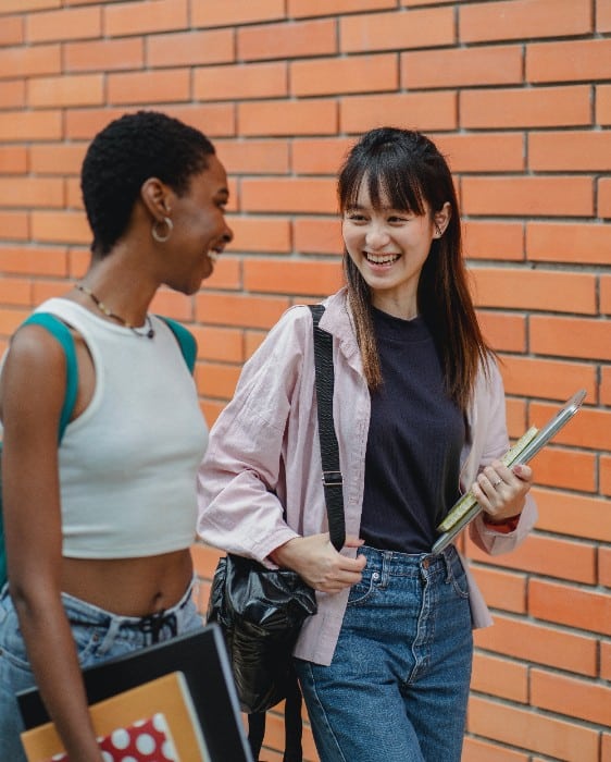 Two happy female graduate students going to class and smiling