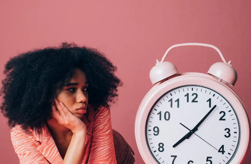 Female MBA student looking at clock and waiting to be off the waitlist