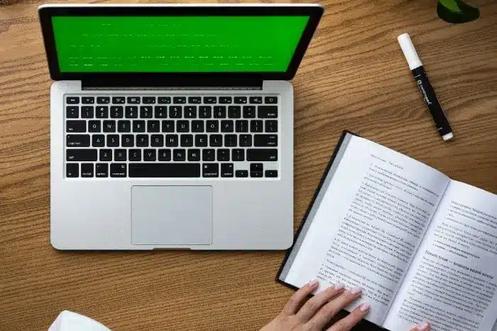 Computer book and pen for GMAT prep with hand of student