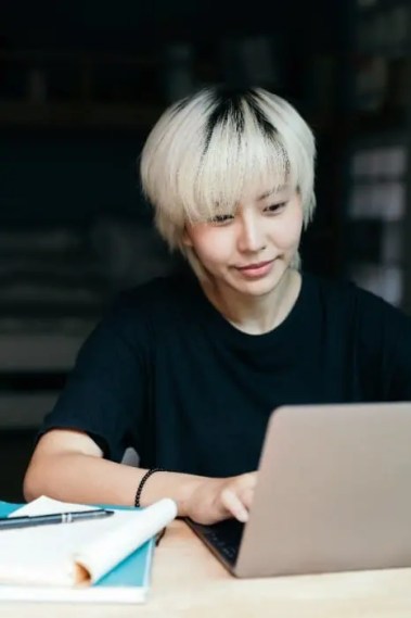 bleached blond student looking at laptop