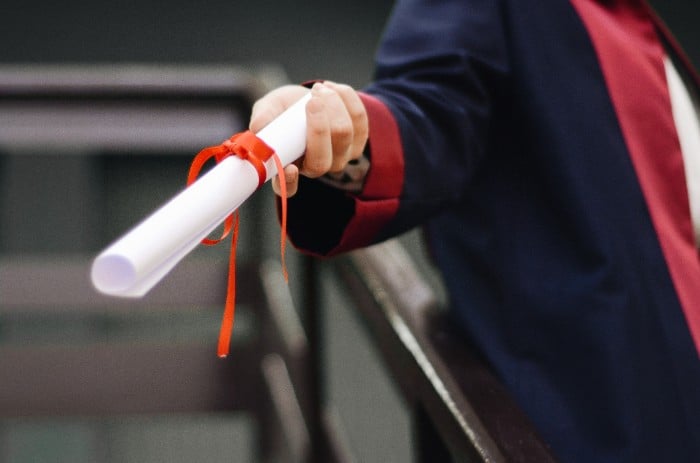 professor handing phd diploma to student