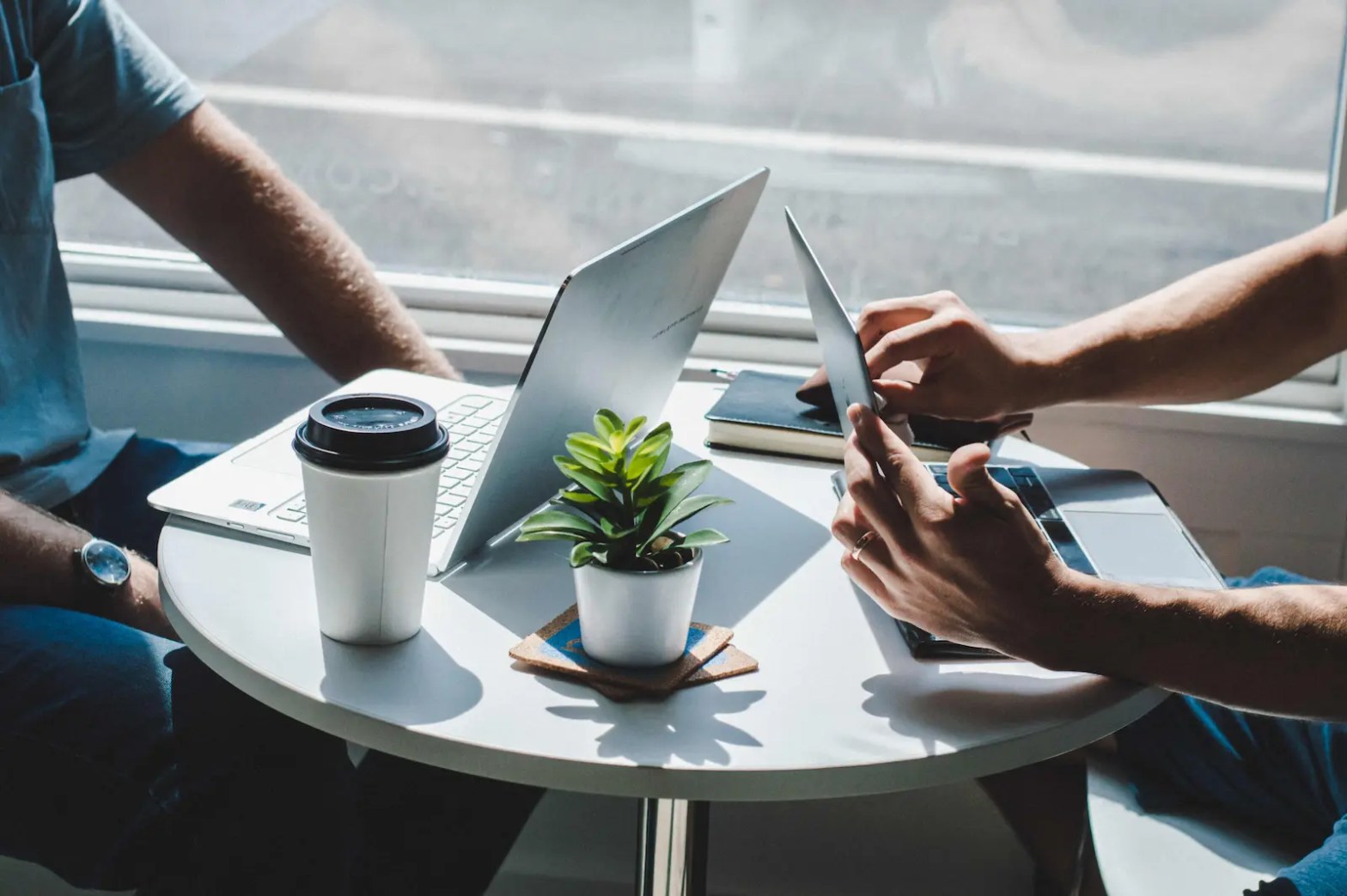 Two students hands and coffee by window