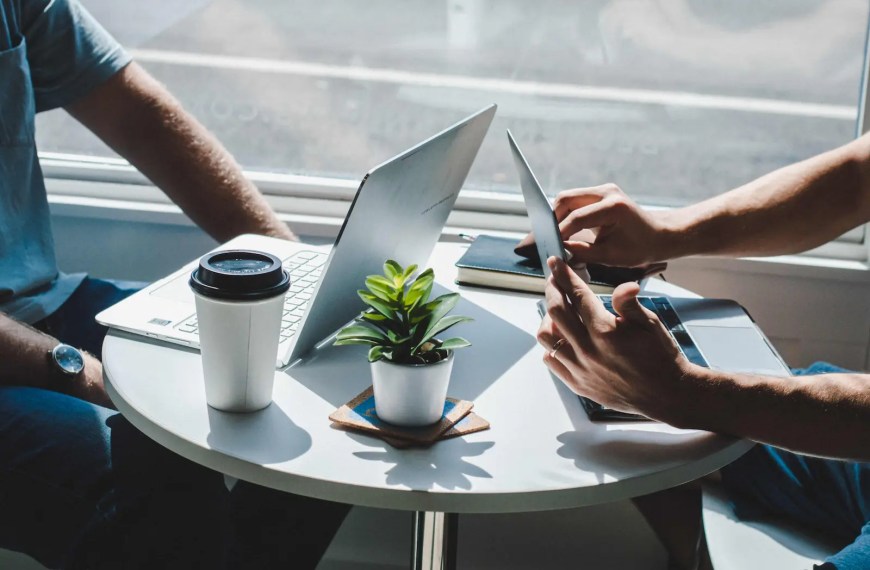 Two students hands and coffee by window