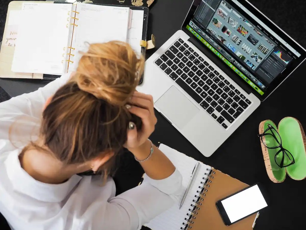 girl stressing out about her kellogg essays holding her head in front of computer