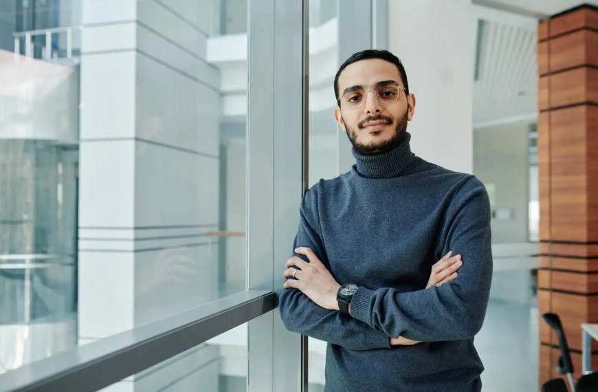 Confident young professional standing by a window in a modern office environment