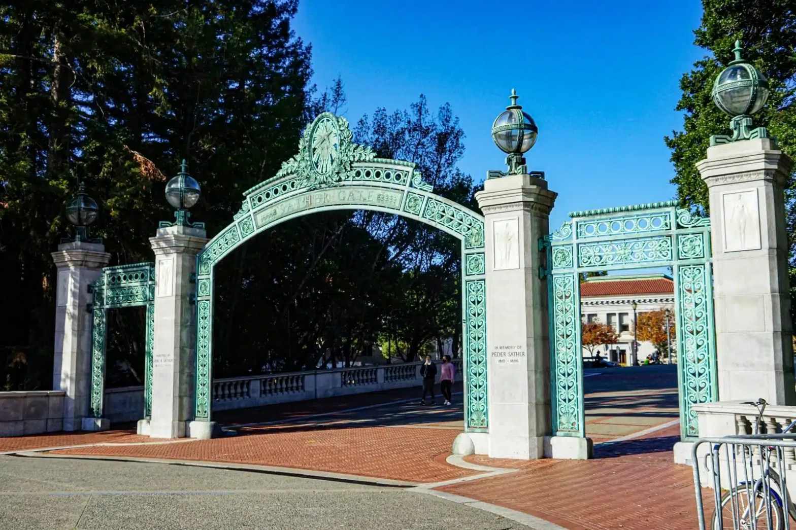 Entrance gate of the University of California, Berkeley, with intricate ironwork and bright blue sky in the background.