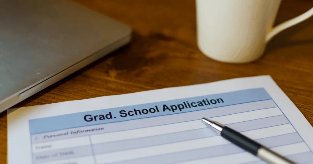 Graduate School Application Form with Pen and Laptop