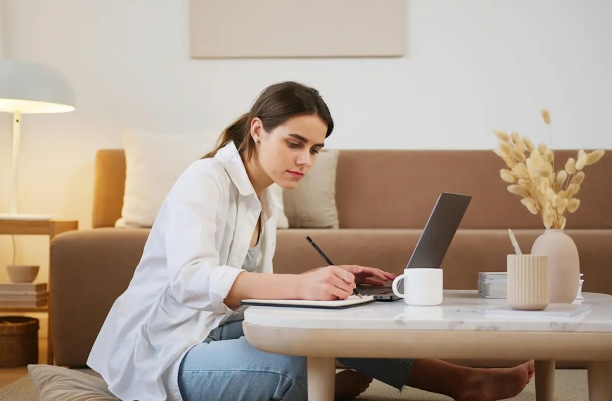 Graduate school applicant writing a statement of purpose at home with laptop and notebook