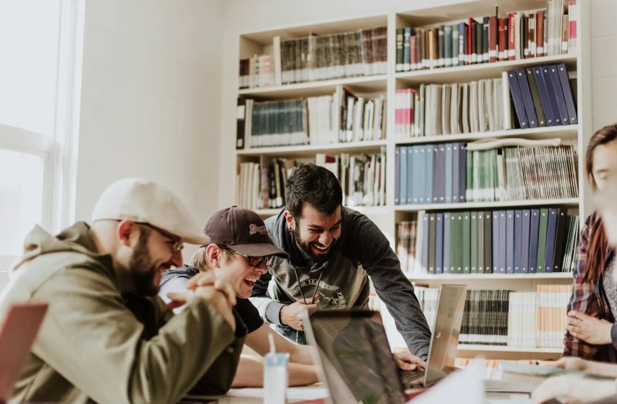 A group of graduate students in a university library working together on laptops — representing collaboration and academic success in the best masters programs for psychology.