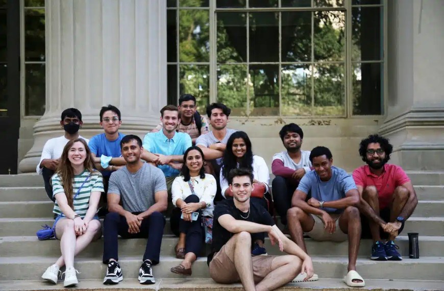 Graduate students seated outdoors in front of university building — illustrating how hard it is to get into a master’s program