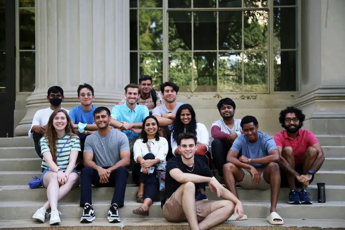 Graduate students seated outdoors in front of university building — illustrating how hard it is to get into a master’s program